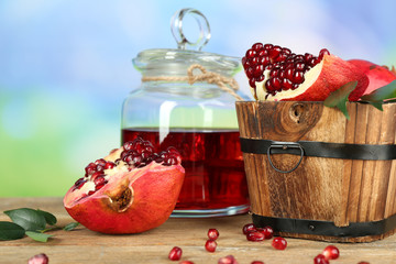 Pomegranate seeds and juice on wooden table on light blurred background