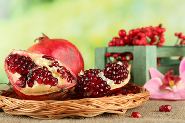 Pomegranate seeds on wicker tray on green blurred background