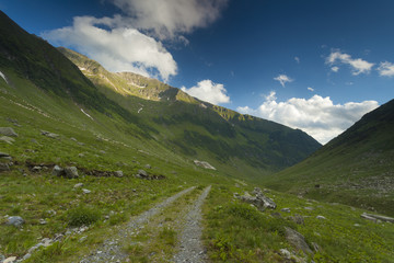 Dirt road in the mountain with blue sky and clouds above