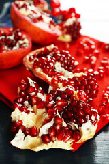 Pomegranate seeds on wooden table and red napkin, closeup