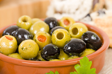 Olives - Bowl of a variety of black and green olives with herbs and olive oil.
