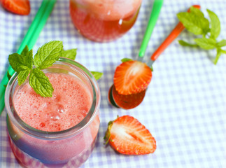 Fresh strawberry and watermelon juice decorated with mint on checkered table cloth and blue wooden background