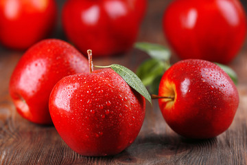 Red apples with droplets on wooden table, closeup
