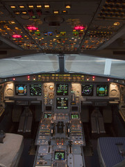 Airbus A330 airplane's cockpit with front,overhead and pedestrian panel taken on ground at dusk.