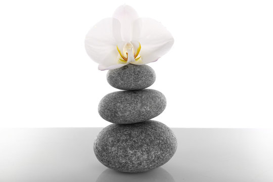 Stack of spa stones with orchid flower isolated on white
