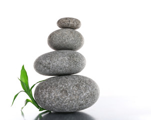 Fototapeta na wymiar Stack of spa stones with green leaves isolated on white