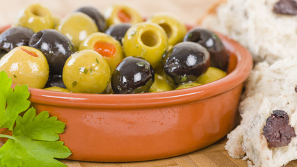 Olives - Bowl of a variety of black and green olives with herbs and olive oil.
