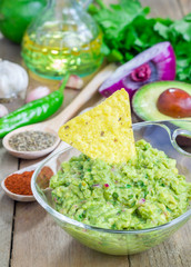 Bowl with chunky guacamole with ingredients on backgroung