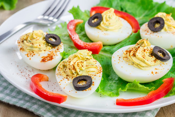 Spicy deviled eggs garnished with olives and paprika