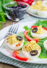 Spicy deviled eggs garnished with olives and paprika