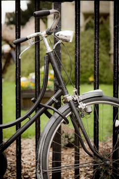 Locked bicycle. An old fashioned bicycle with a retro dynamo locked to some railings by a Cambridge University college.
