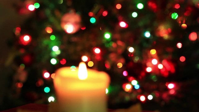 Flame of candle on blurred blinking christmas lights
