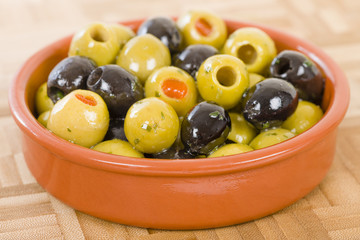 Olives - Bowl of a variety of black and green olives with herbs and olive oil.
