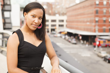 A young woman with a cityscape backdrop looks at the viewer.