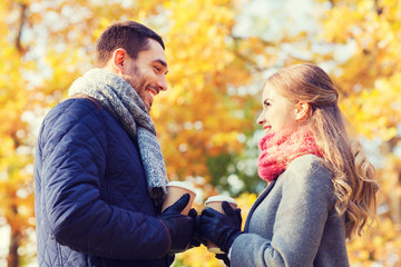 Fototapeta premium smiling couple with coffee cups in autumn park