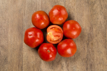 Some tomatoes over a wooden surface on a tomato field as backgro