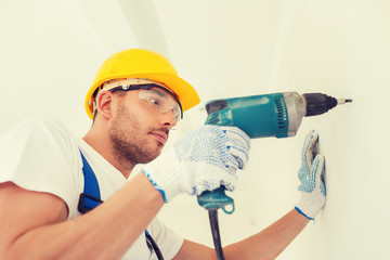 builder in hardhat working with drill indoors