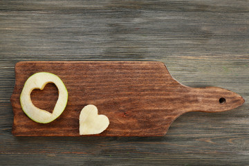 Apple slice with cut in shape of heart on wooden background