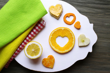 Orange slice with cut in shape of heart and different fruits on table close up