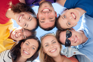 smiling friends in circle on summer beach