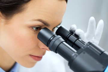 close up of scientist looking to microscope in lab