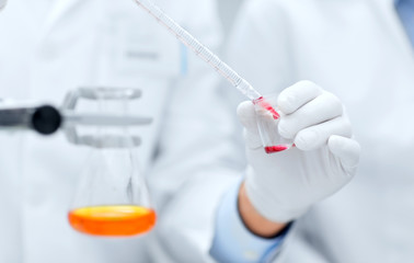 close up of scientists filling test tube in lab
