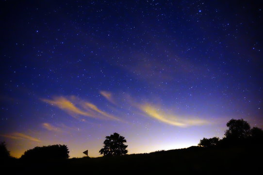 Starry Night Scene with Light Pollution Reflecting off Whispy Clouds in the Countryside