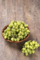 Green grapes in a basket over a wooden surface on a grape field