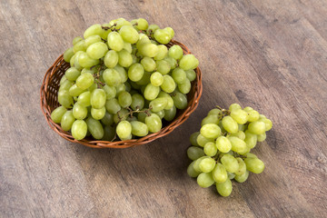 Green grapes in a basket over a wooden surface on a grape field