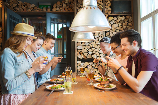 happy friends with smartphones picturing food