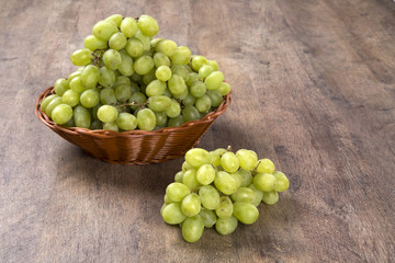 Green grapes in a basket over a wooden surface on a grape field