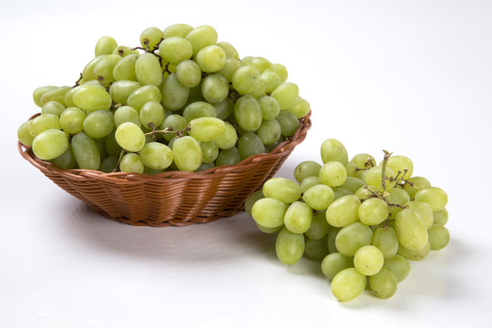 Green grapes in a basket over a wooden surface on a grape field