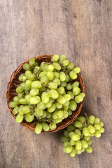 Green grapes in a basket over a wooden surface on a grape field