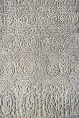 Detail close-up of the textured pattern of a carving in relief on a rough weathered stone wall at the Angkor Wat temple complex in Cambodia