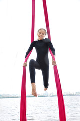 cheerful child training on aerial silks outdoor