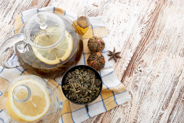 Ripe lemon, cinnamon and fruit drink in glass teapot on wooden