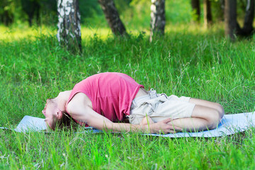 young man doing yoga and gymnastics on the grass