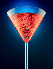 Obrazy na Szkle  Kieliszek czerwonego martini na pięknie lśniącym na niebieskim tle
