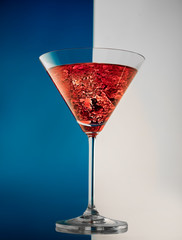 Glass of red martini on a white-blue background with ice