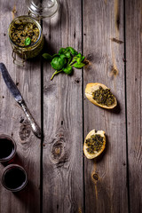 Pesto, wine and two slices of baquette on the table.