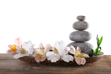Obraz na płótnie Canvas Spa stones with alstroemeria and bamboo in wooden tray with water isolated on white