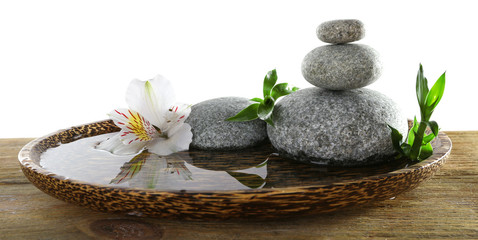 Spa stones with alstroemeria and bamboo in wooden tray with water isolated on white