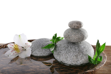 Fototapeta na wymiar Spa stones with alstroemeria and bamboo in wooden tray with water isolated on white