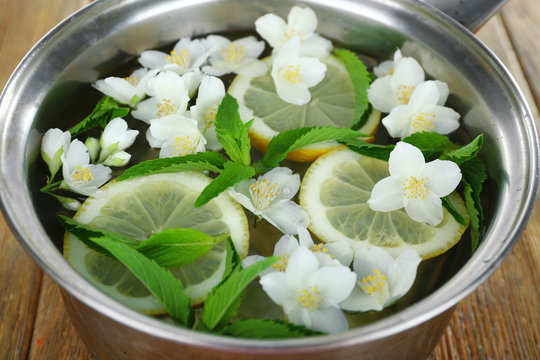 Cold refreshing summer drink with mint and slices of lemon in pan close up