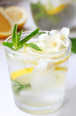 Glass of cold refreshing summer drink with mint and slices of lemon on table close up