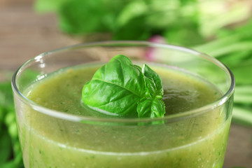 Glass of green healthy juice with spinach and peas on table close up