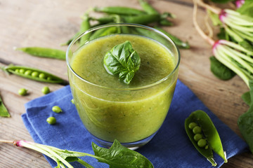 Glass of green healthy juice with spinach and peas on table close up