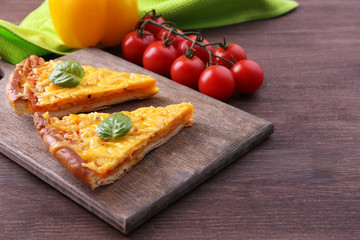 Slices of tasty cheese pizza with basil and vegetables on table close up