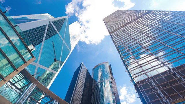 Timelapse video of office buildings with reflection of clouds, zooming in