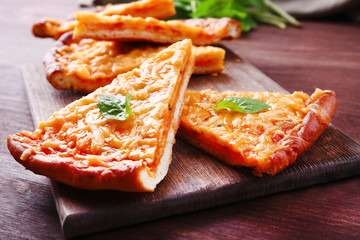 Slices of tasty cheese pizza with basil on table close up